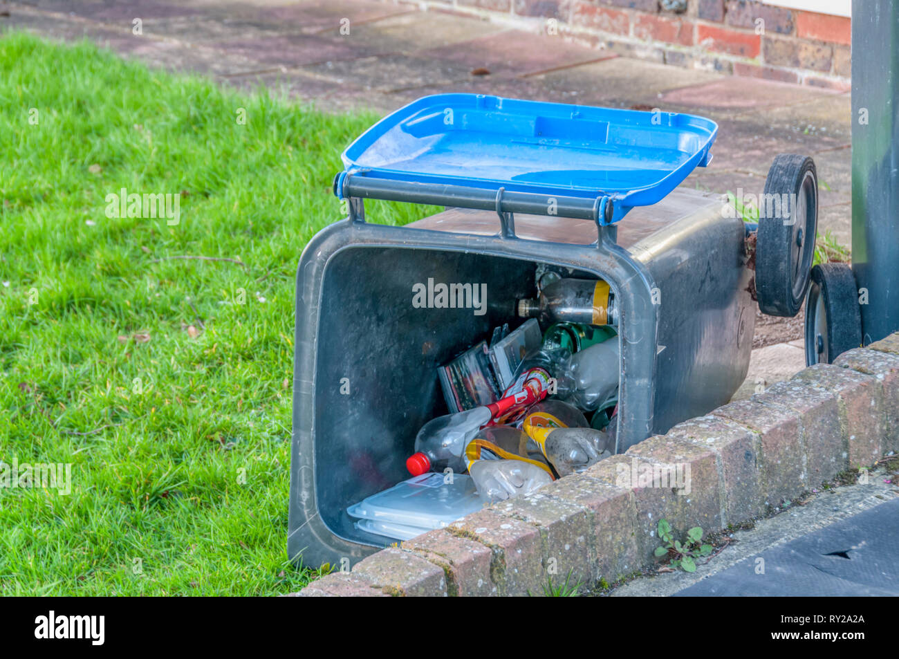 A Wheelie bin put out for domestic rubbish collection blown over in high winds. Stock Photo