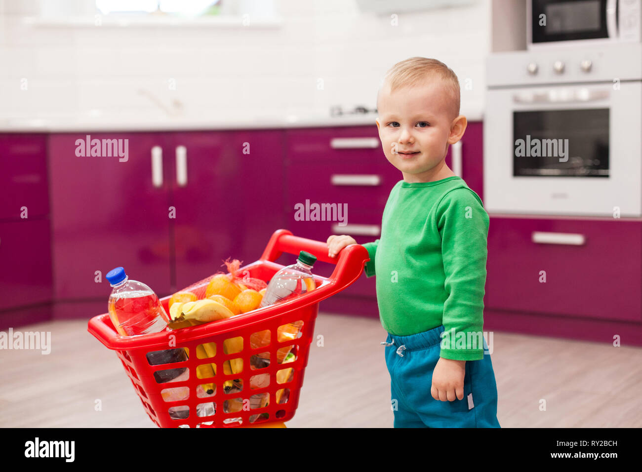 Cheerful little boy with shopping cart. Little kid in casual wear