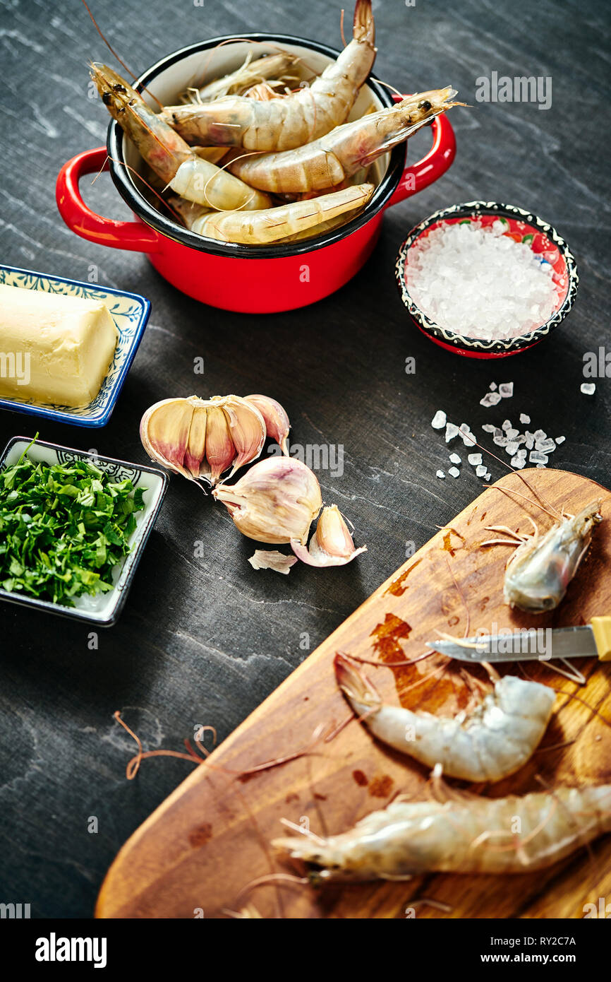 fresh delicious raw tiger prawns in a red pot with parsley, lemon