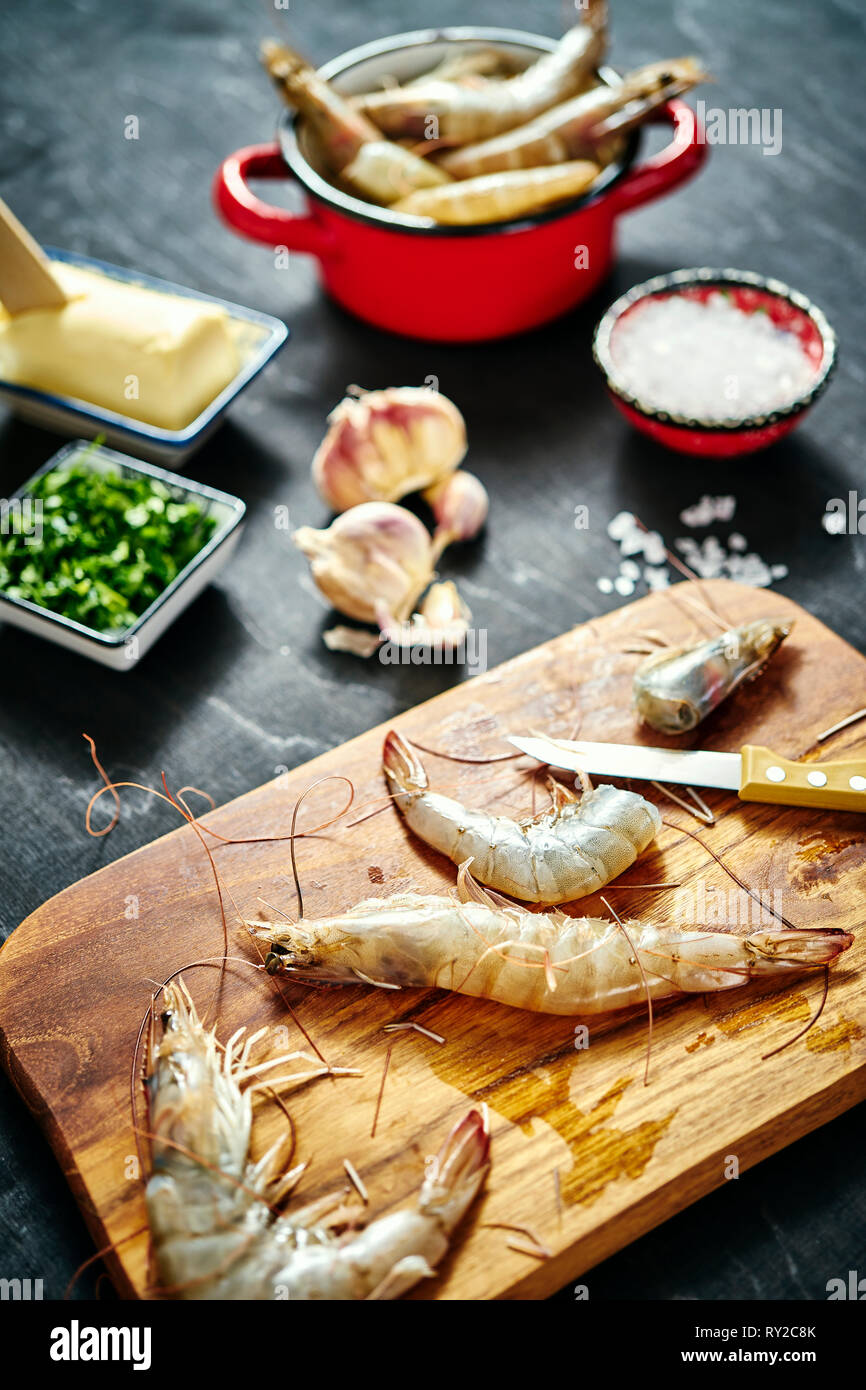 fresh delicious raw tiger prawns in a red pot with parsley, lemon
