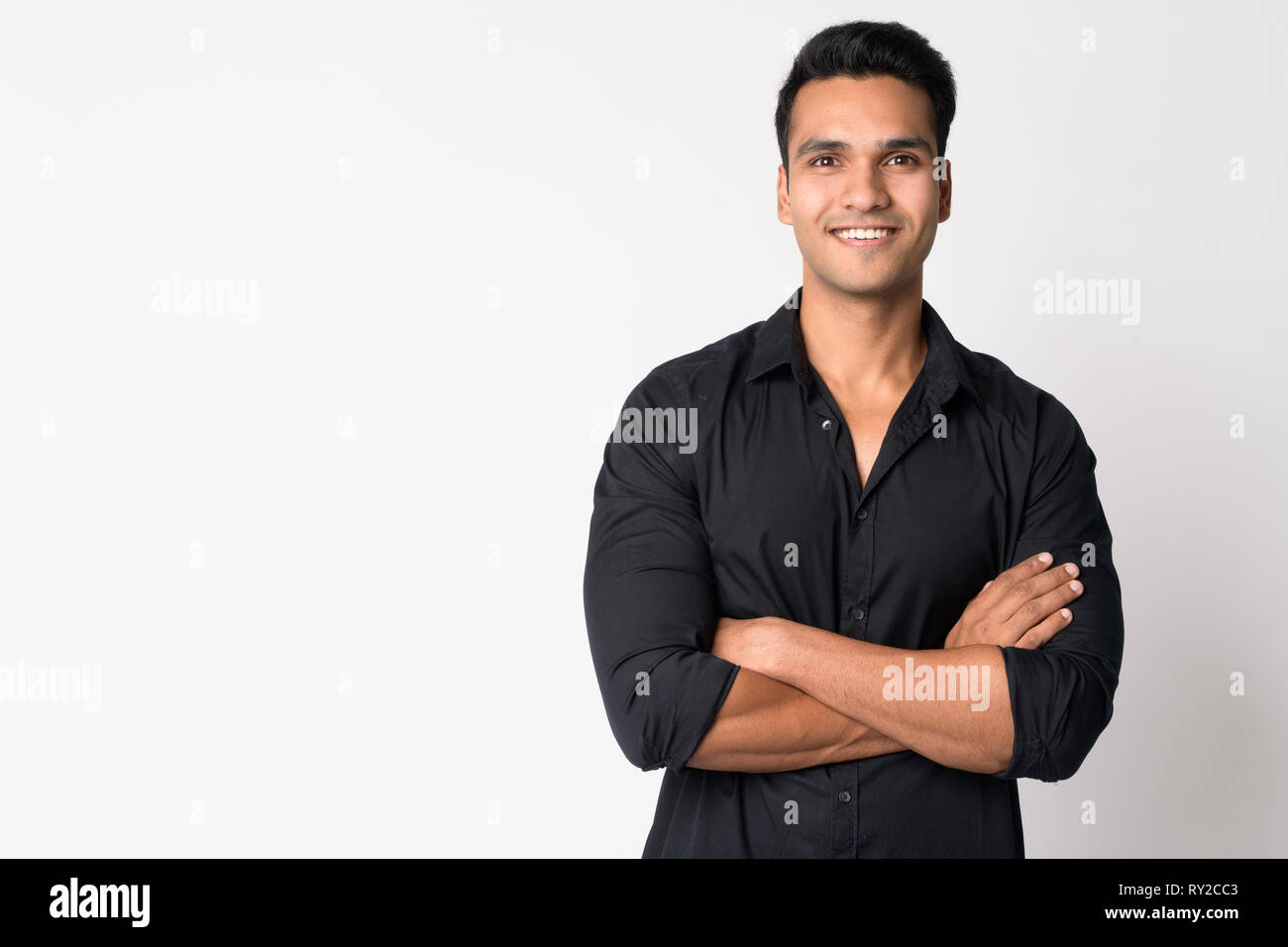 Portrait of young happy Indian businessman smiling with arms crossed ...
