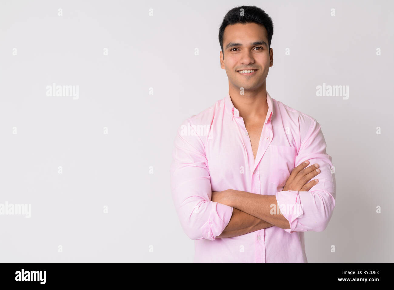 Portrait of young happy Indian businessman smiling with arms crossed ...