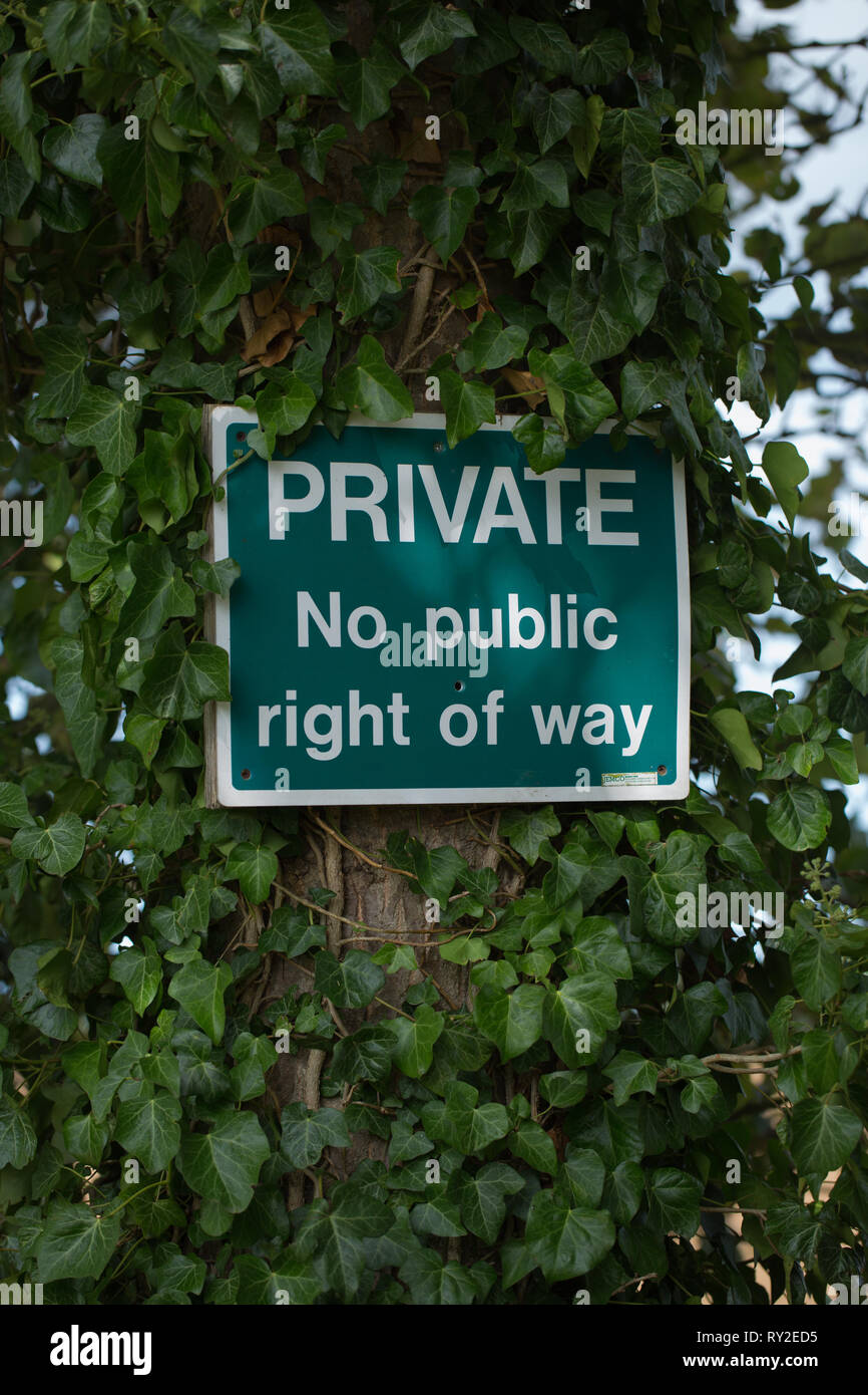 Warning sign on a roadside tree trunk. PRIVATE No public right of way. Entrance to a farmyard. Registering an owners fear of trespass, vandalism, theft, loss of privacy. Norfolk. England. Stock Photo