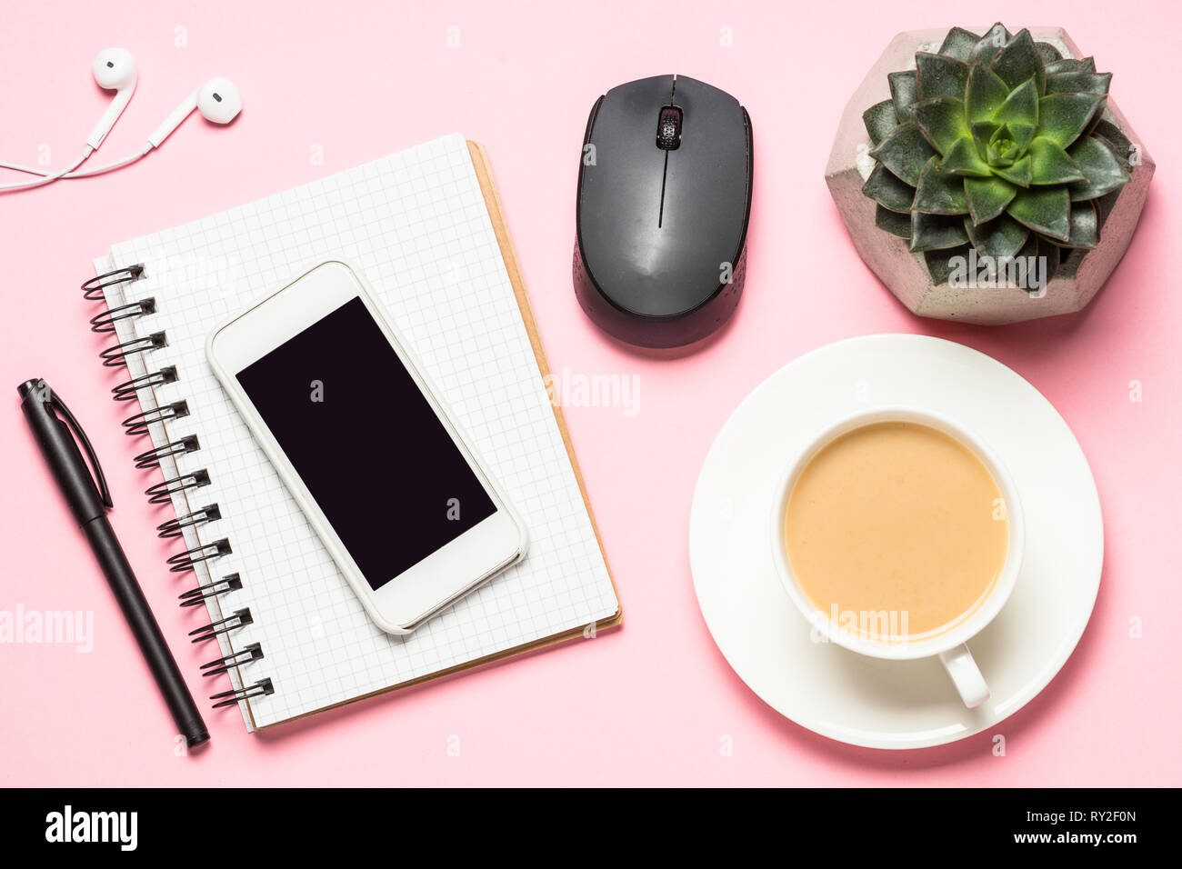 Freelance workplace with notepad, coffee cup, succulent and mouse on pink Stock Photo