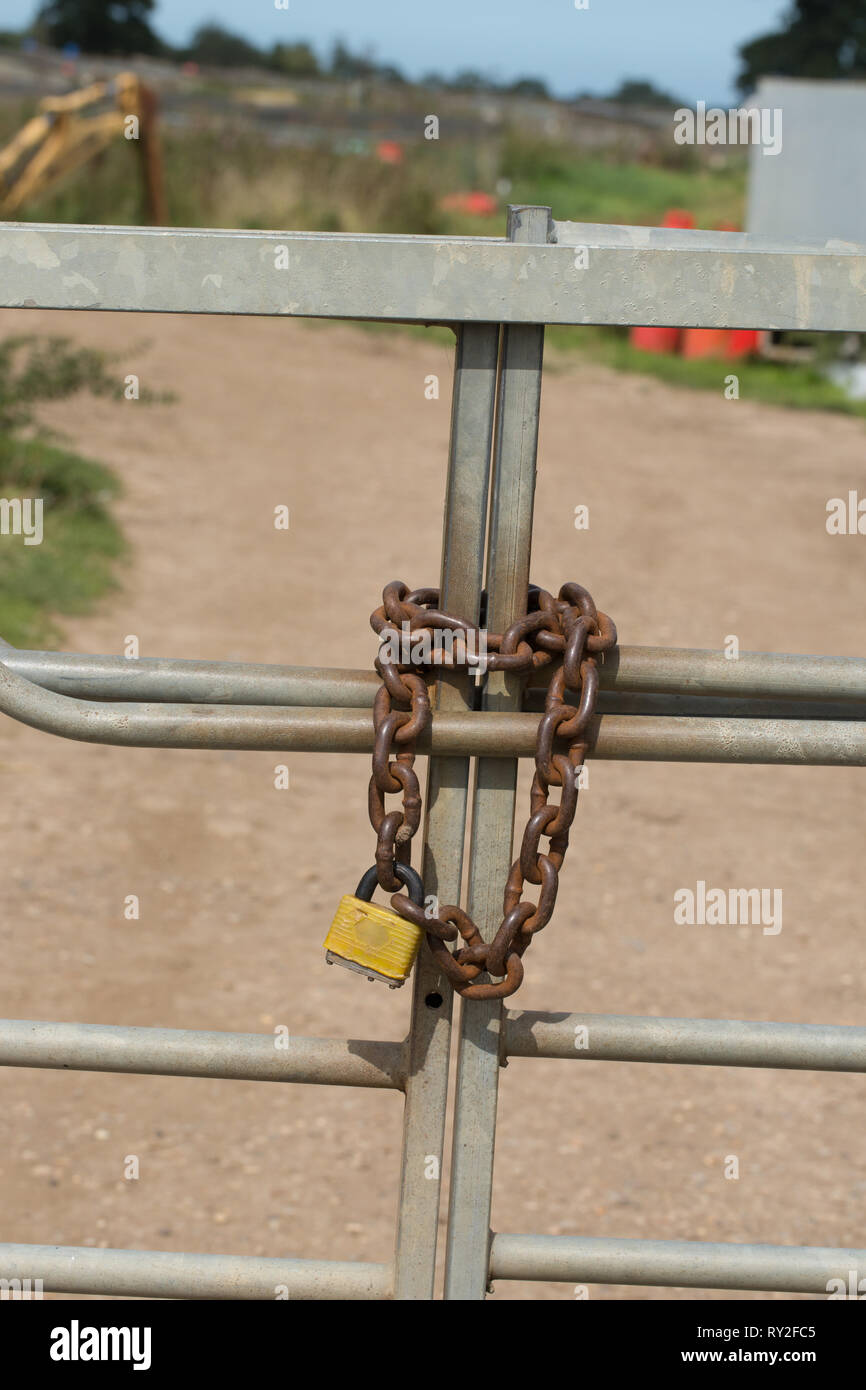 Metal Gates, closed and secured by a heavy-duty metal chain and padlock. Property protection. Practical and, by sight, psychological thinking on the wayward passersby. Stock Photo