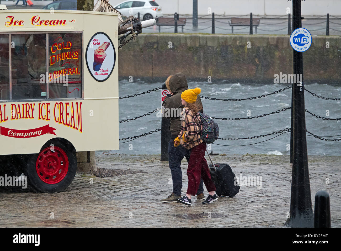 A woman and a young girl look at an ice cream van whilst out walking on a very wet and windy day in Liverpool UK. Stock Photo