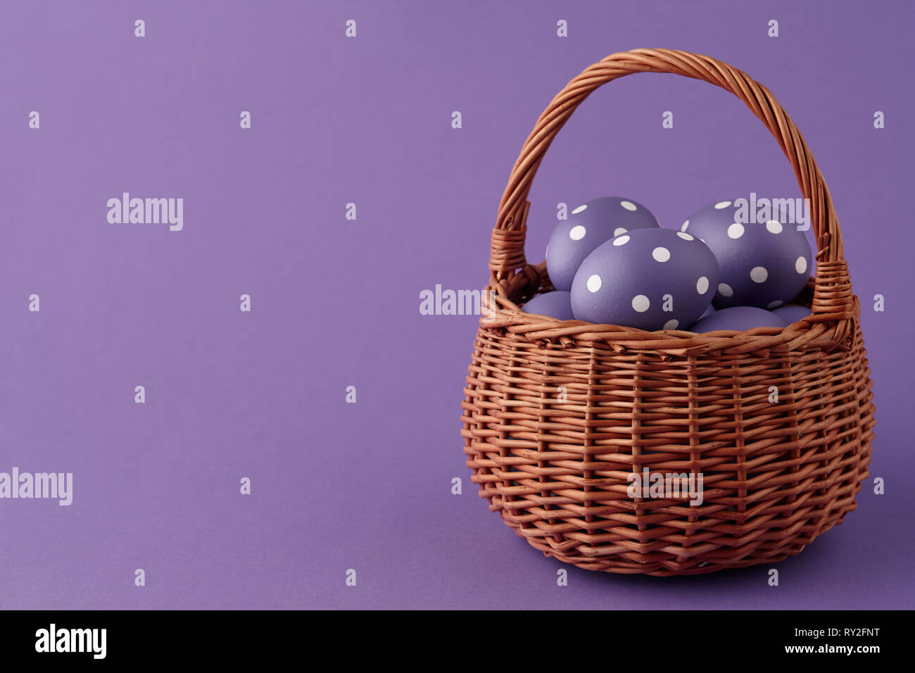 Wicker basket full of purple painted Easter eggs with dots on purple ...