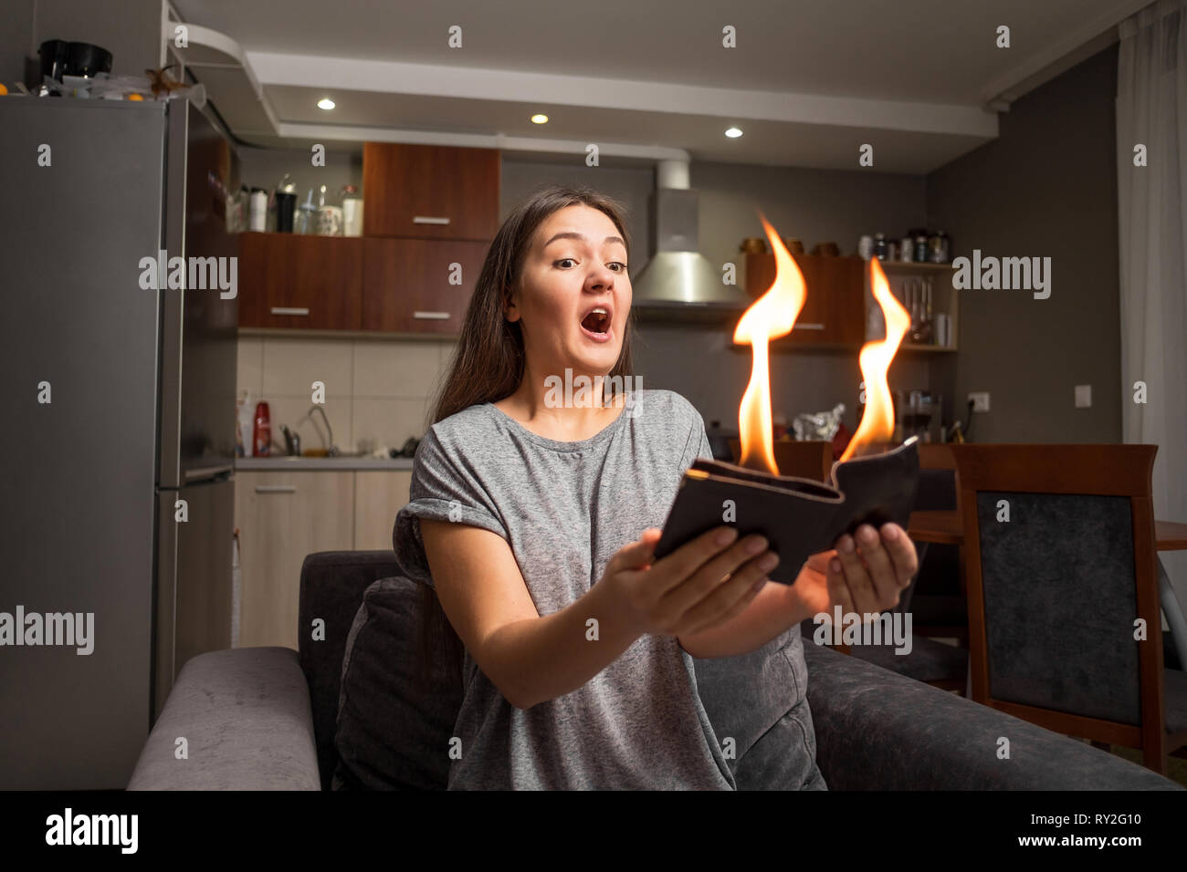 young woman holding a wallet, wallet on fire, surprised girl, magic