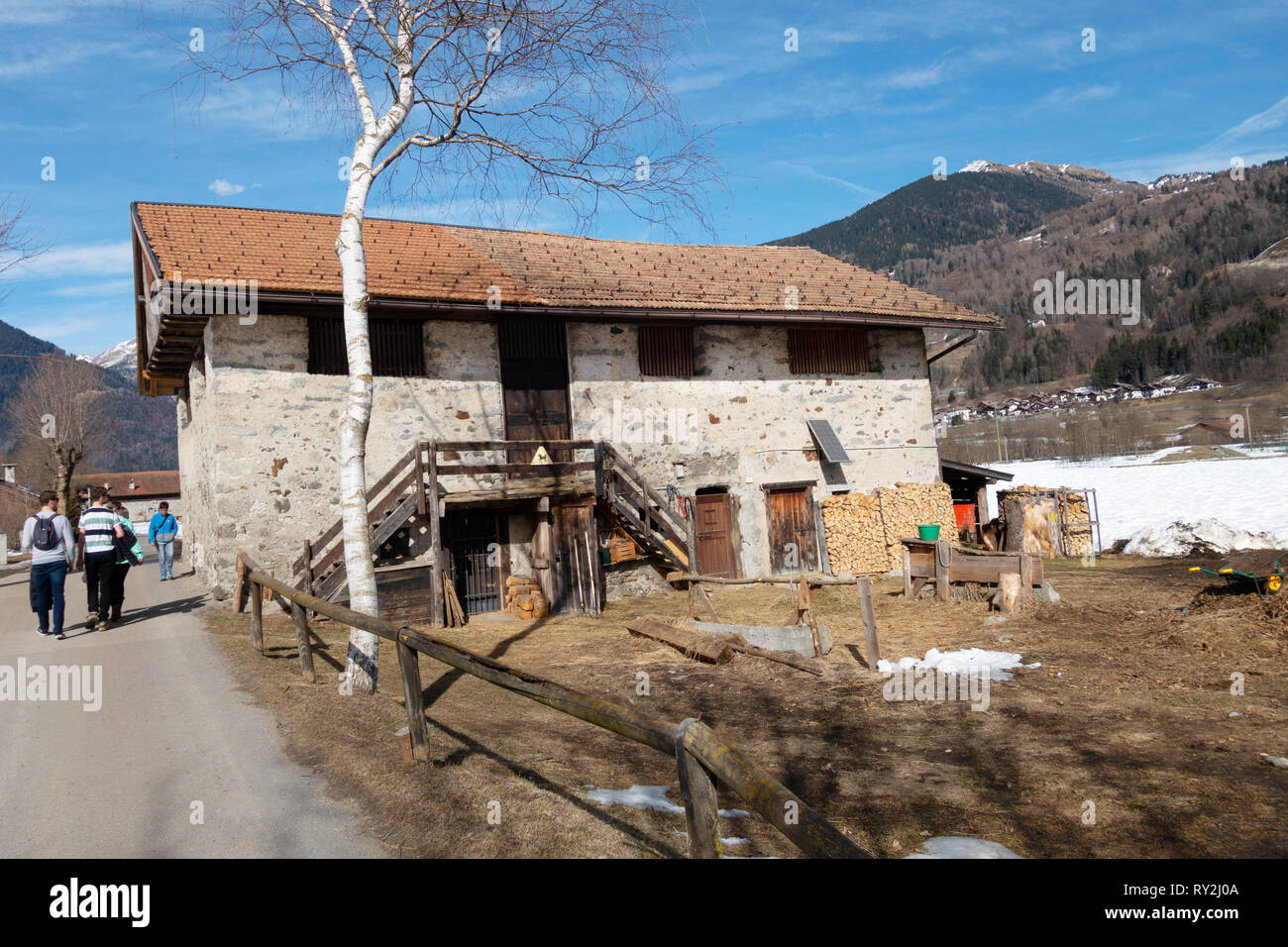 People walking past a farmhouse, the village of Pinzolo in the Brenta Dolomites, northern Italy Europe Stock Photo