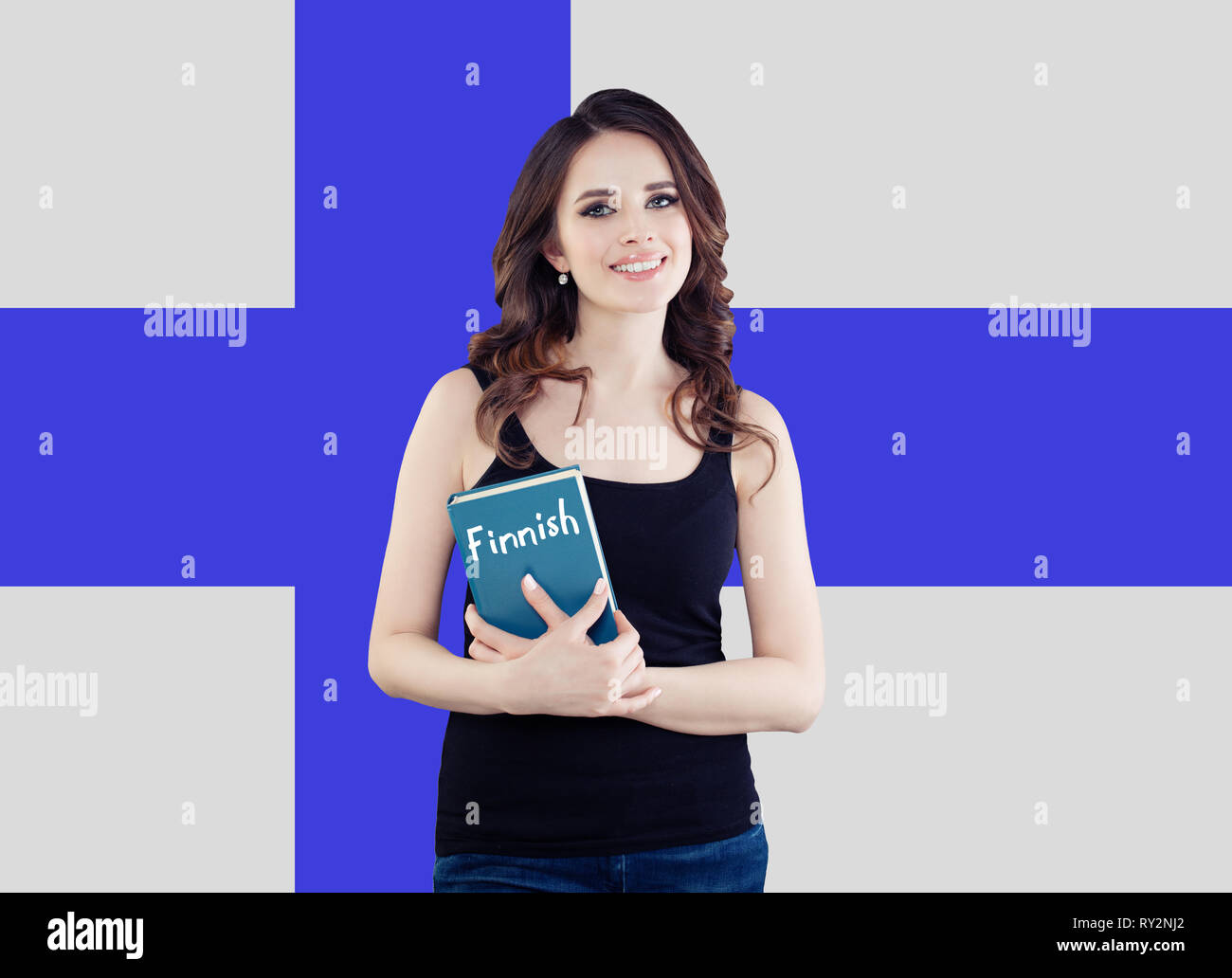 Travel in Finland and learn finnish language. Happy smiling woman holding phrasebook against the Finnish flag background Stock Photo