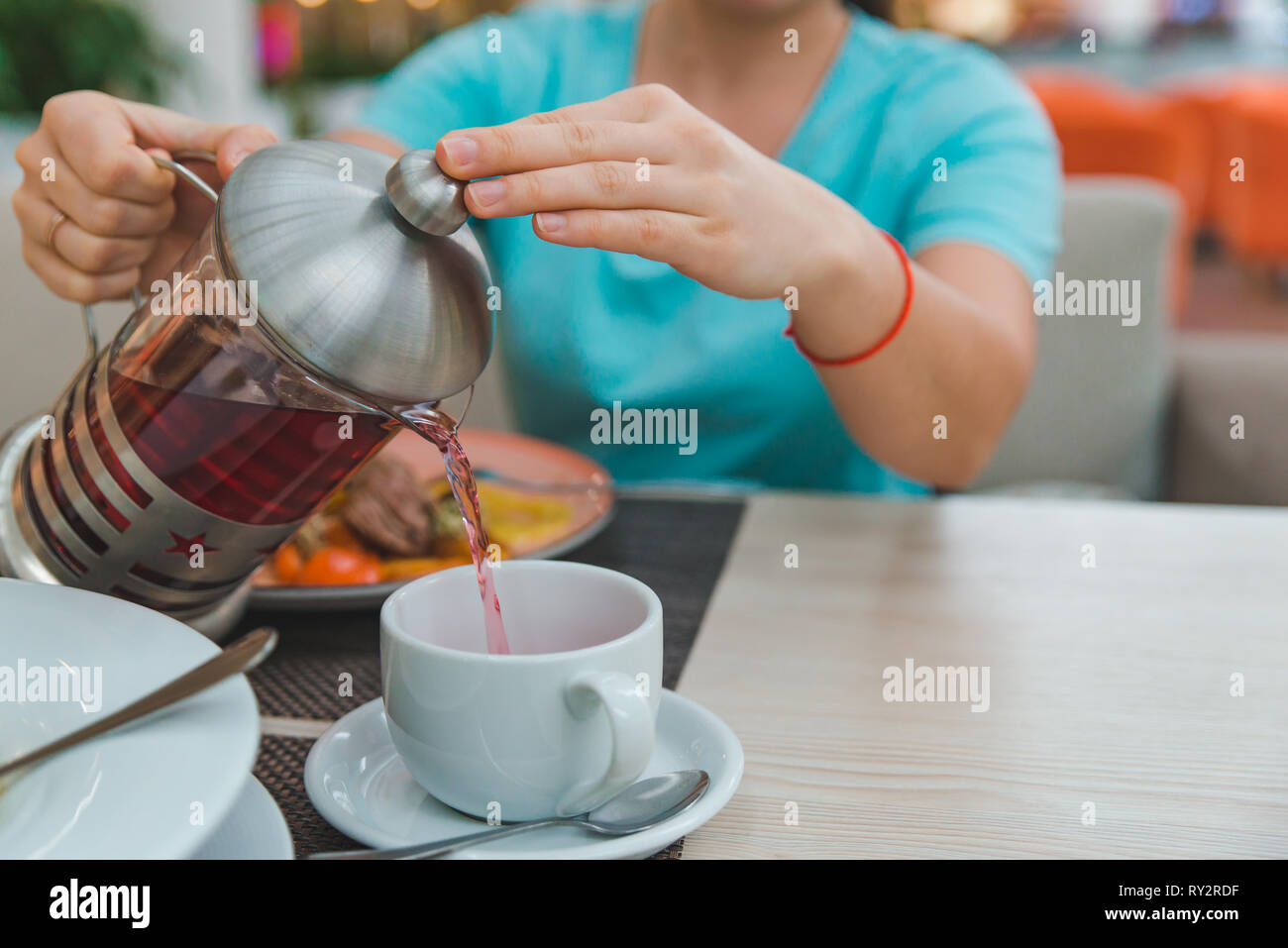 woman hands close up pouring fruit tea from kettle. french press Stock