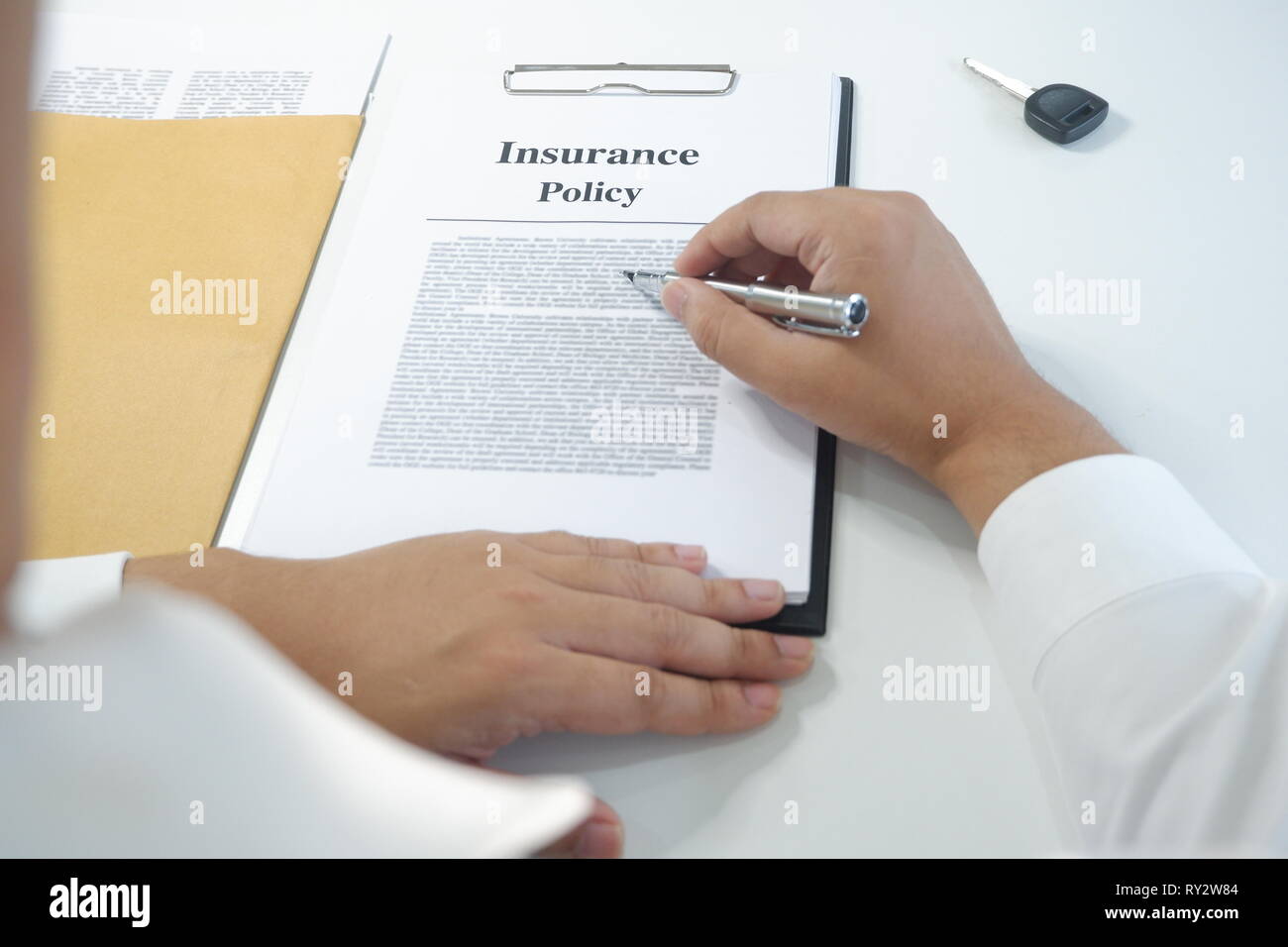 Insurance Document Reading close-up man reading insurance policy, contract with car key on table ...