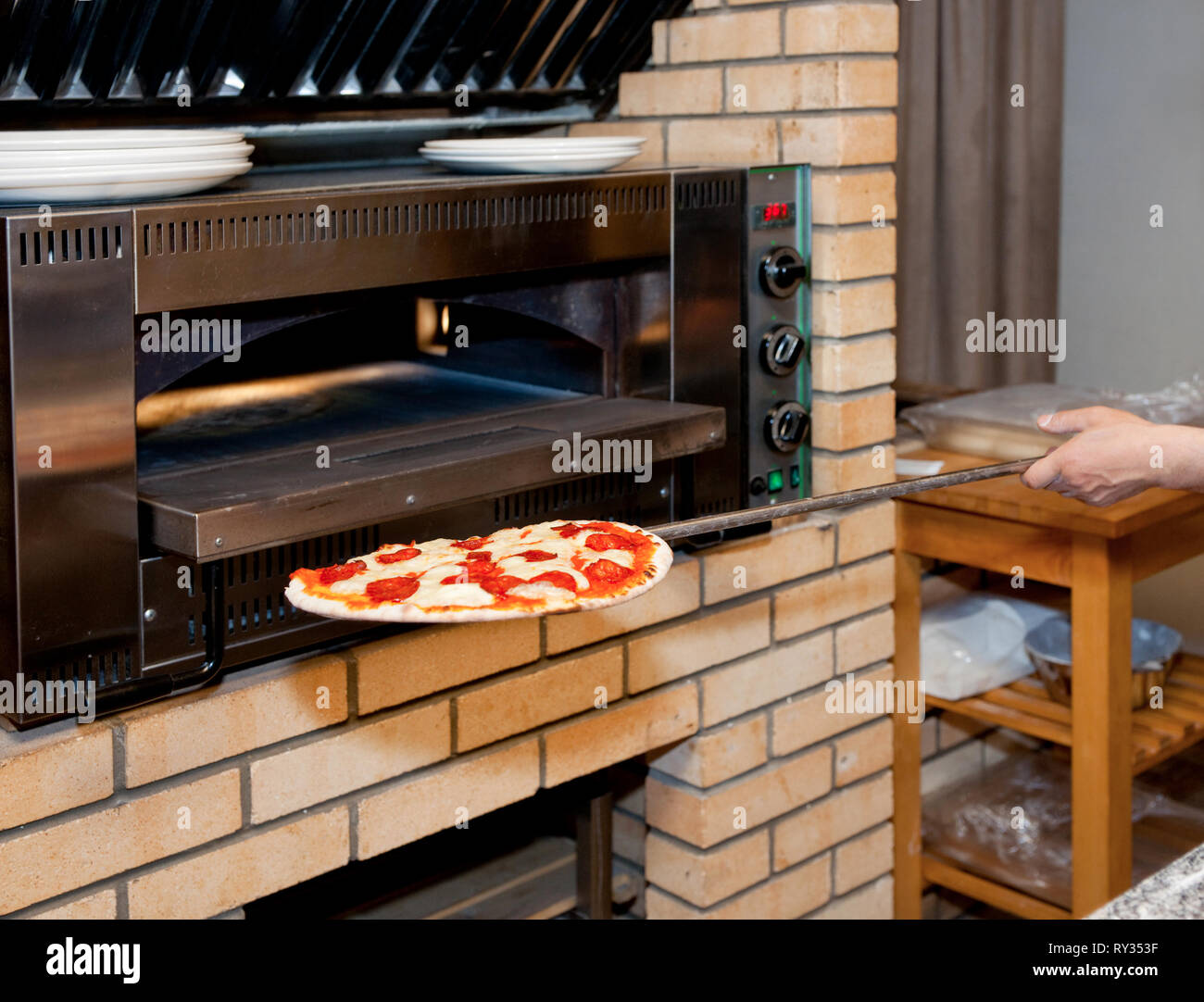 Man inserting pizza in oven, reataurant kitchen Stock Photo