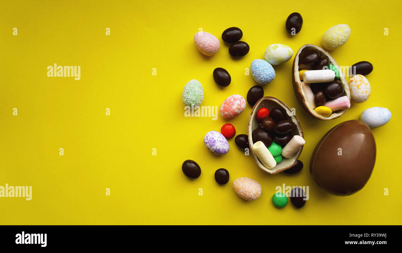 Delicious chocolate easter eggs, sweets on bright yellow background Stock Photo
