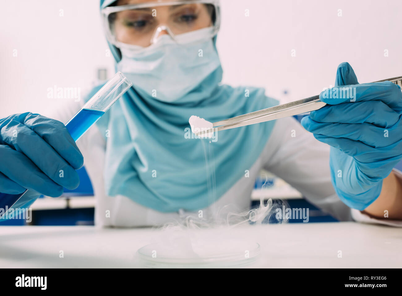 cropped view of female muslim scientist holding test tube with tweezers
