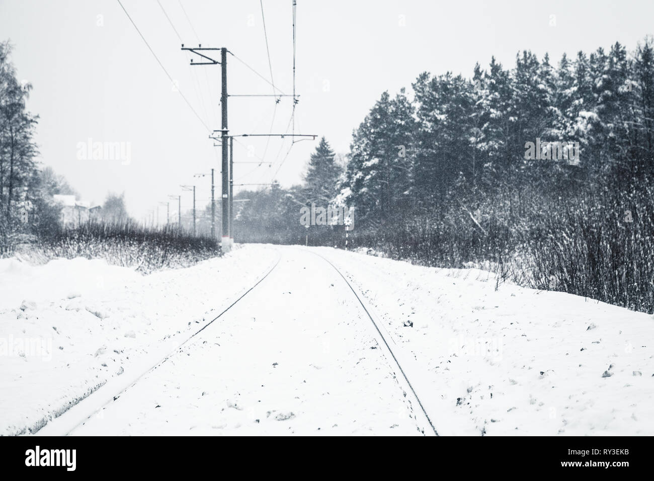 Winter landscape with an empty rural railway going through the forest Stock Photo