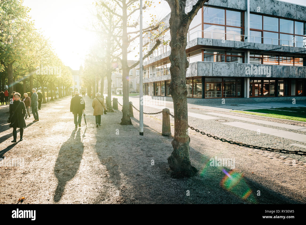 Karlsruhe, Germany - Oct 29 2017: Sunlight flare over adults and seniors walking on alley Schloss Bezirk near Federal Constitutional Court building Bundesverfassungsgericht  Stock Photo