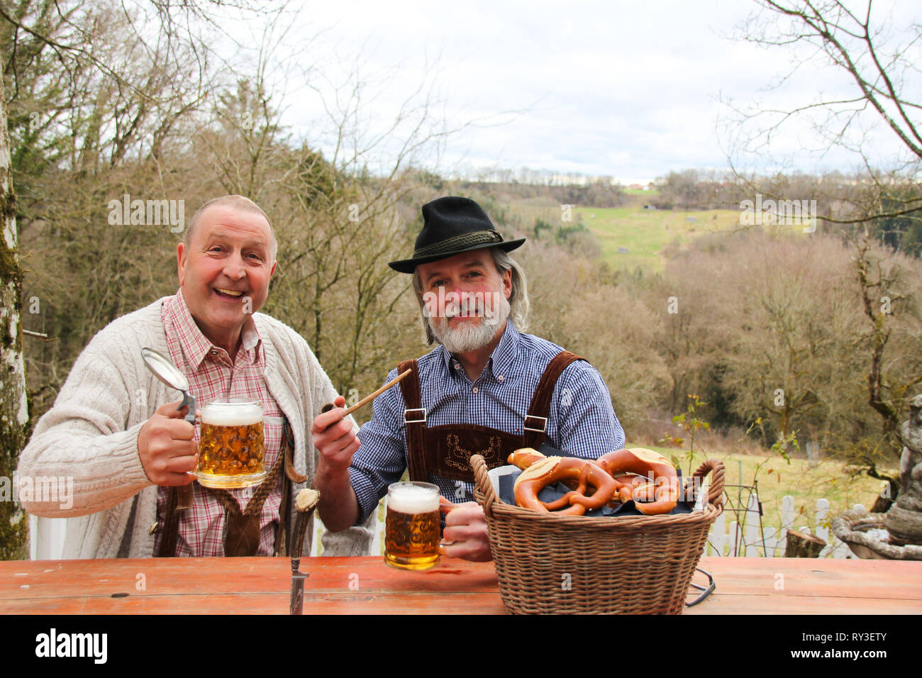 Two men wearing Bavarian October festival strive, drinking beer and feeling happy outdoors Stock Photo