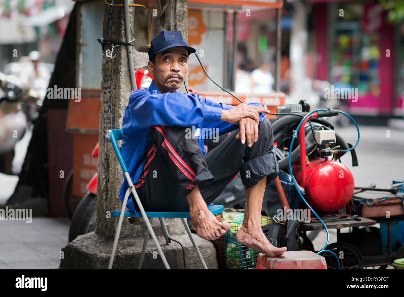 Asian homeless man barefoot with a gas cylinder in a street of hanoi, Vietnam Stock Photo