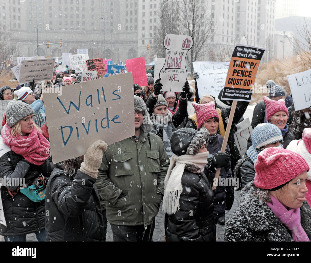 2019 Women's March participants hold signs including 'Walls Divide' as they march through a snowstorm in Public Square in Cleveland, Ohio, USA. Stock Photo