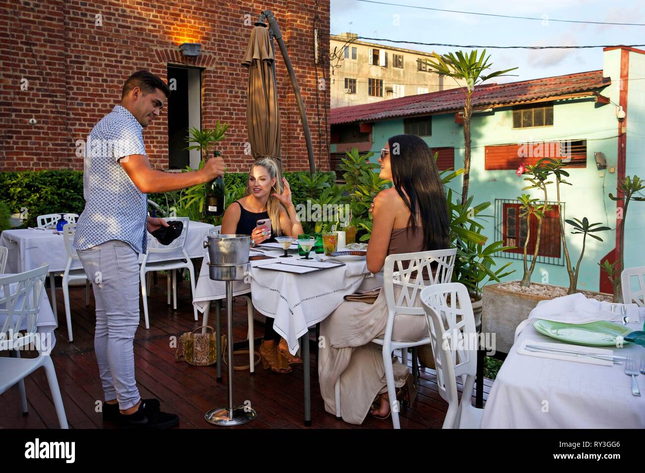 Cuba, La Havana, Vedado, server presenting champagne to two 
