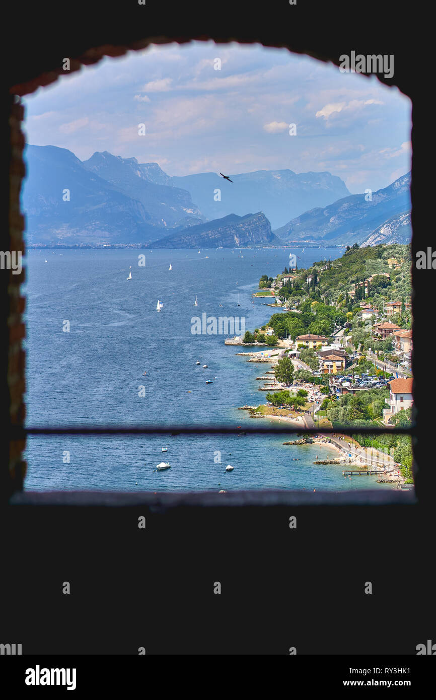 View of the Lake Garda through an old wooden framed window. Portrait format. Stock Photo