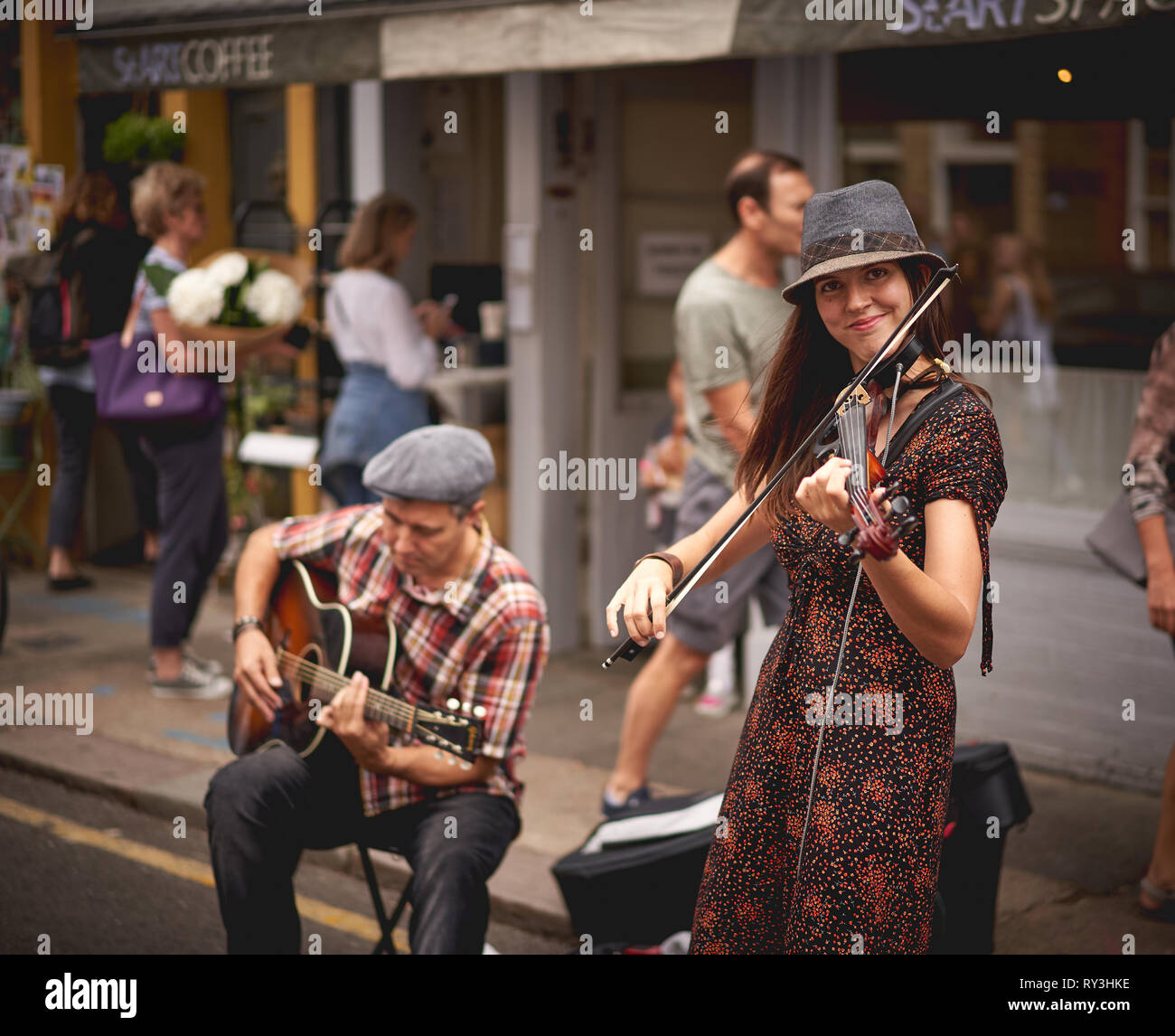 London, UK - August, 2018. A guitarist and a violinist performing at the Columbia Road Flower Market. Stock Photo