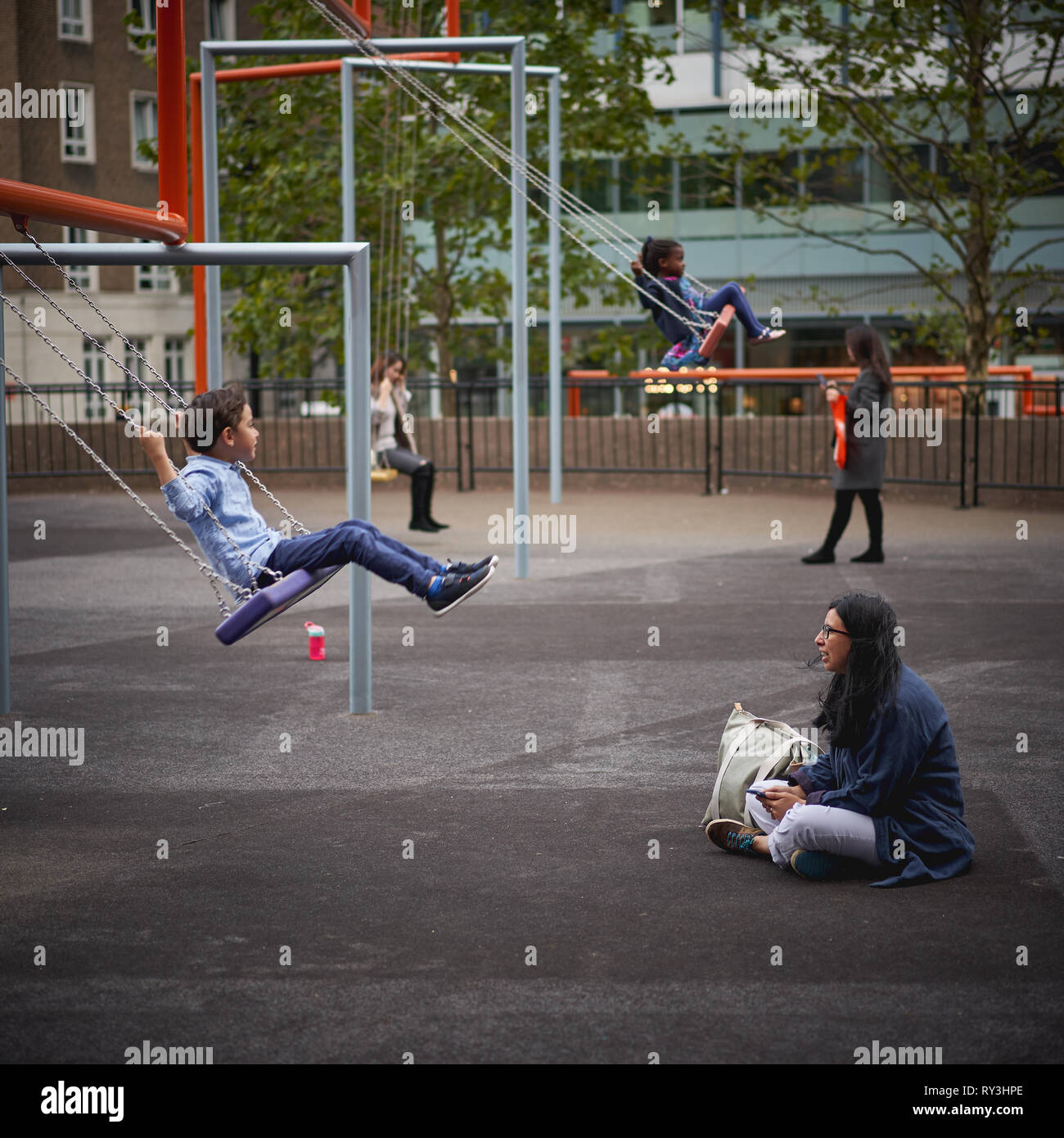 London, UK - October, 2018. Kids playing on swings outside the Tate Modern Museum in South Bank. Stock Photo