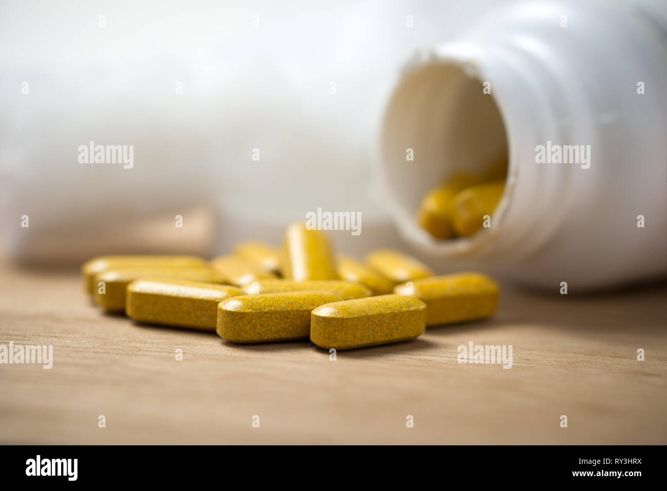 Dietary supplement tablets pouring out of container Stock Photo