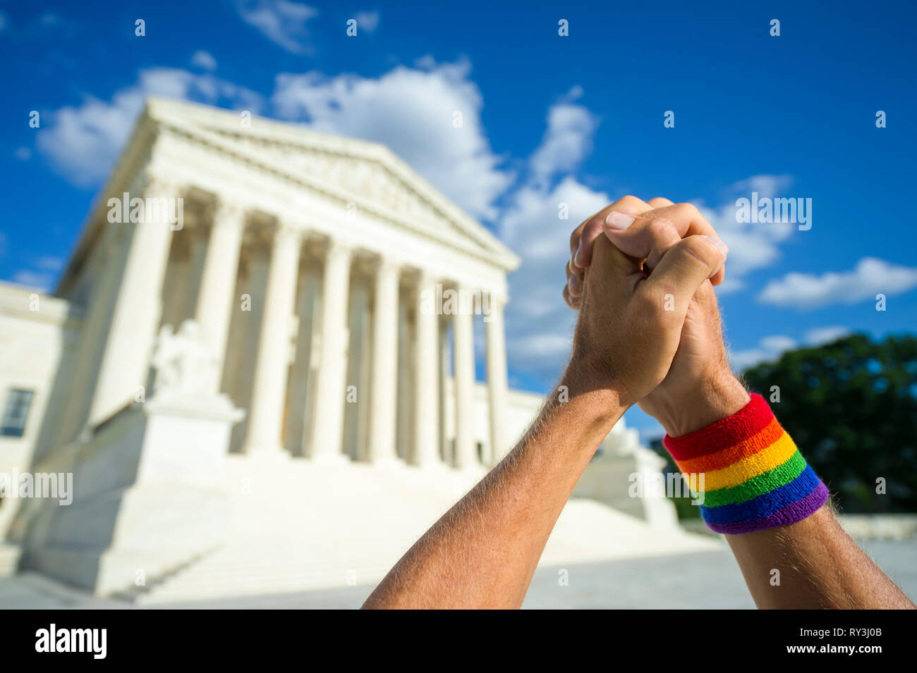 Pleading hands wearing gay pride rainbow flag wristband clasped in prayer outside the Supreme Court building in Washington, DC, USA Stock Photo
