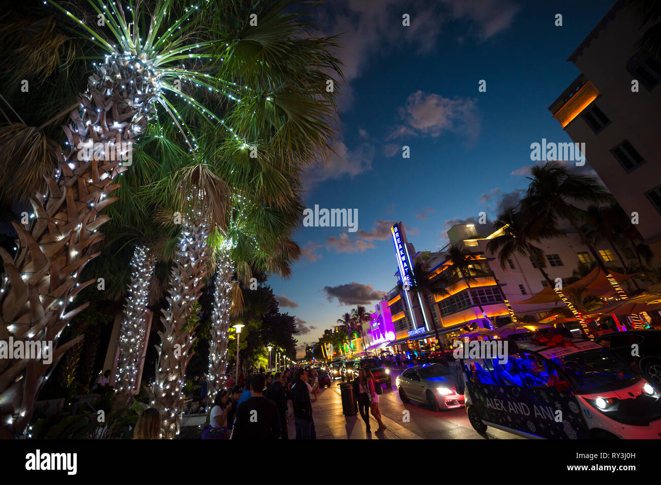 MIAMI - DECEMBER 30, 2018: Visitors stroll along the lights of Ocean Drive, with Art Deco neon lights and holiday palm trees decorated for Christmas. Stock Photo