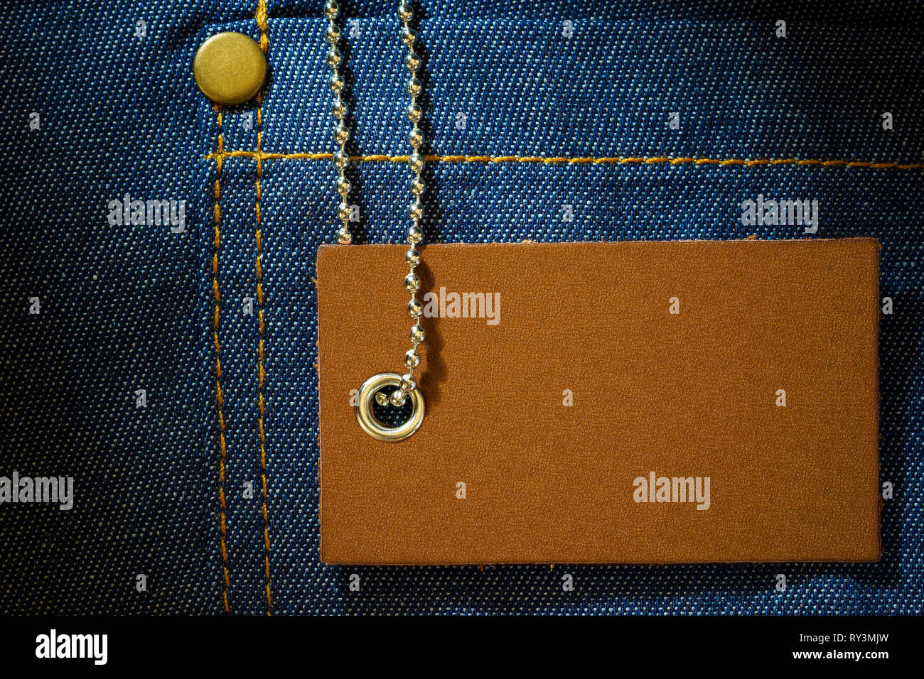 Leather label of product price and stainless steel ball chain on denim clothing. The concept of Fashion jeans. Stock Photo