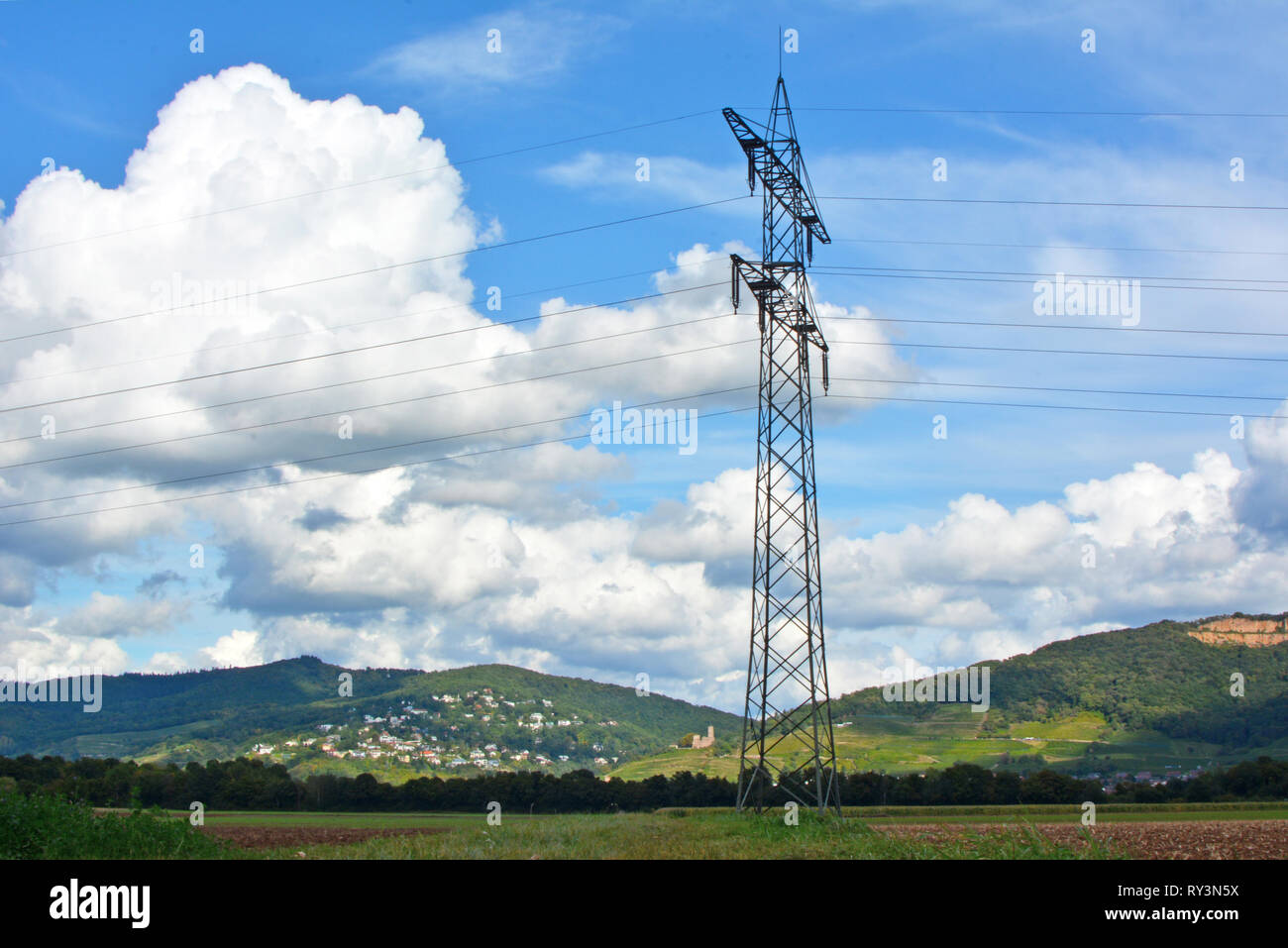 Transmission Tower in front of mountain range and blue sky with clouds Stock Photo