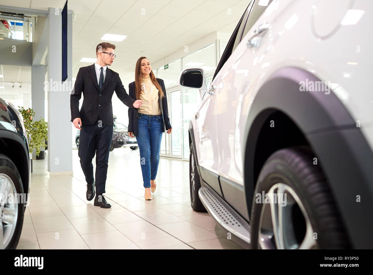 Girl and the salesman choose a car in the auto showroom Stock Photo