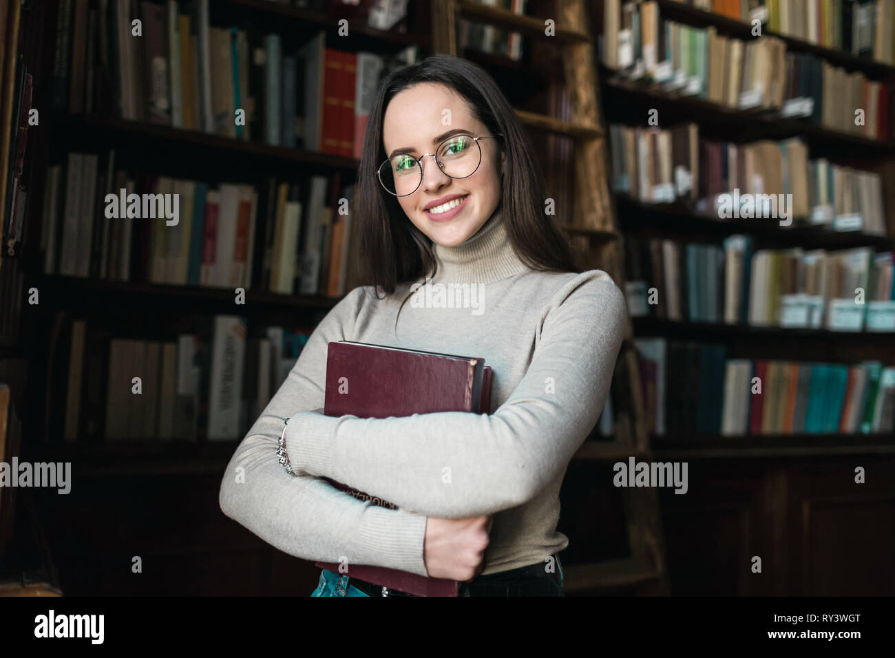 Long haired student girl holding a book and smiling to tge camera Stock ...