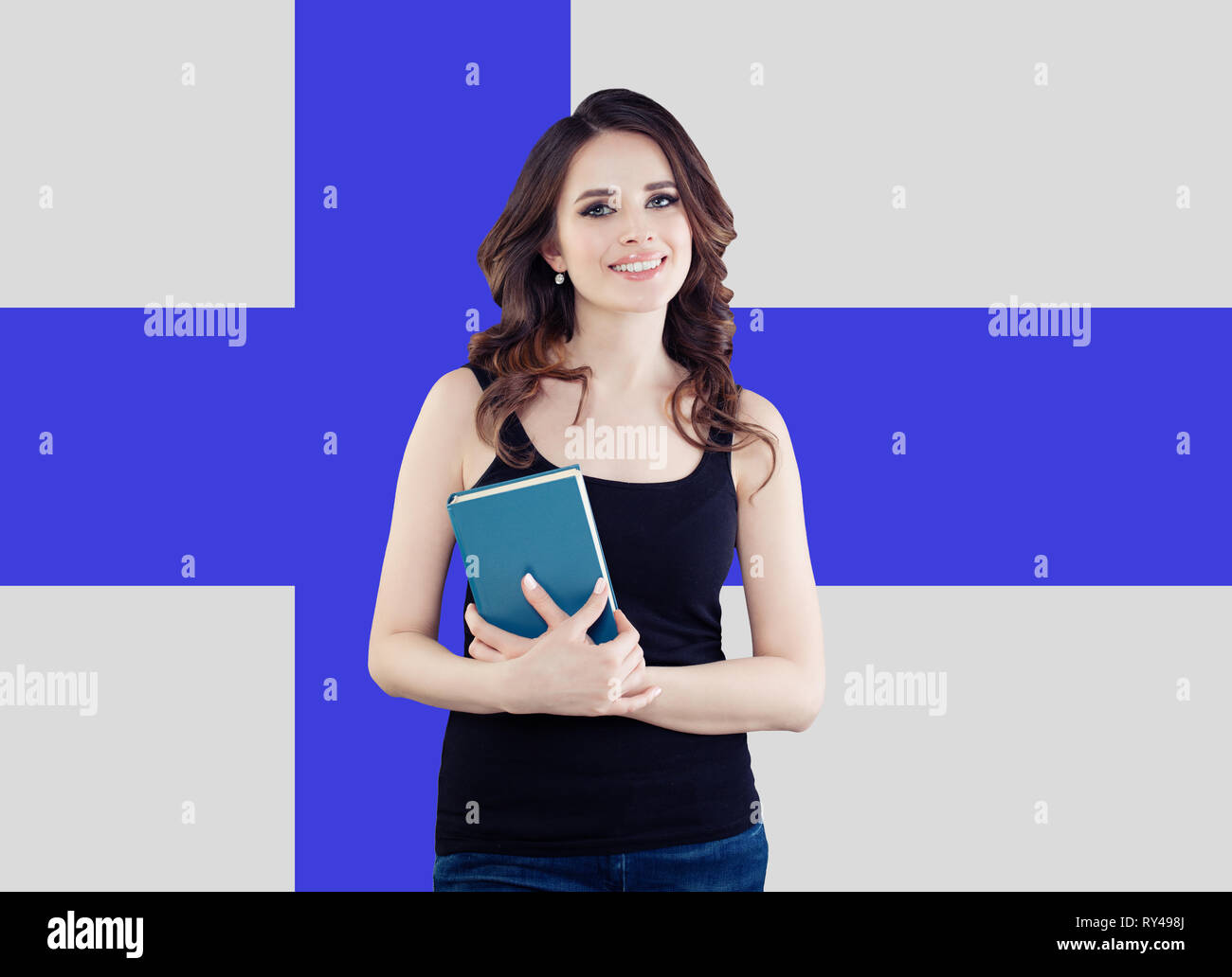 Young woman smiling and posing against the Finnish flag background. Finnish language school and travel concept Stock Photo