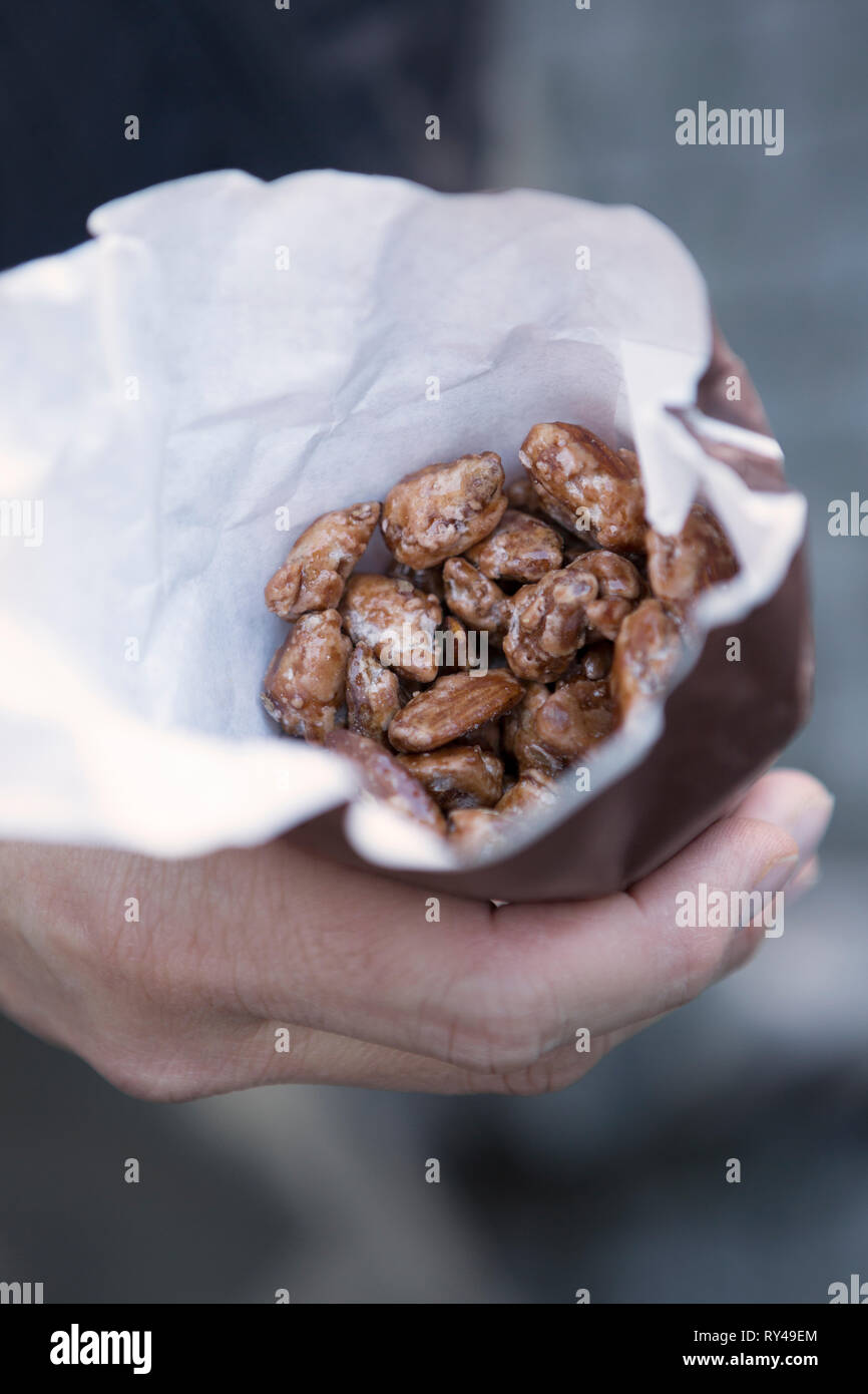 Paper bag of candied nuts held in a man's hand at a German Christmas market Stock Photo