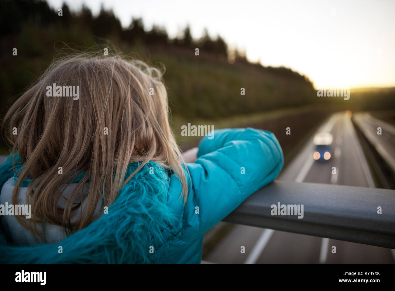 Child watching traffic from a motorway bridge Stock Photo