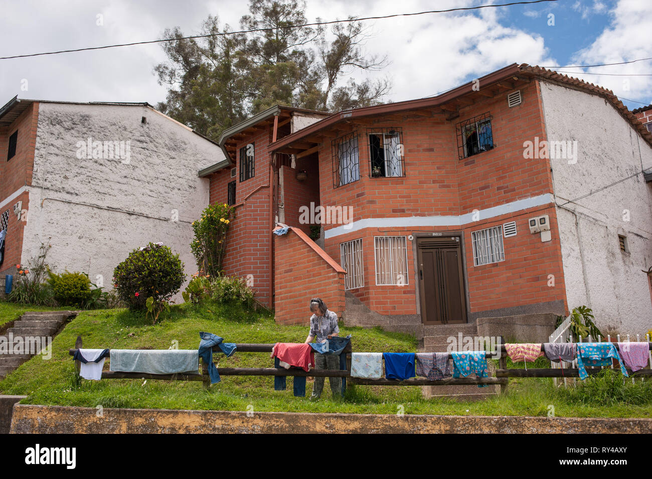 Donmatias, Antioquia, Colombia: an old lady lays her laundry on the garden fence. Stock Photo