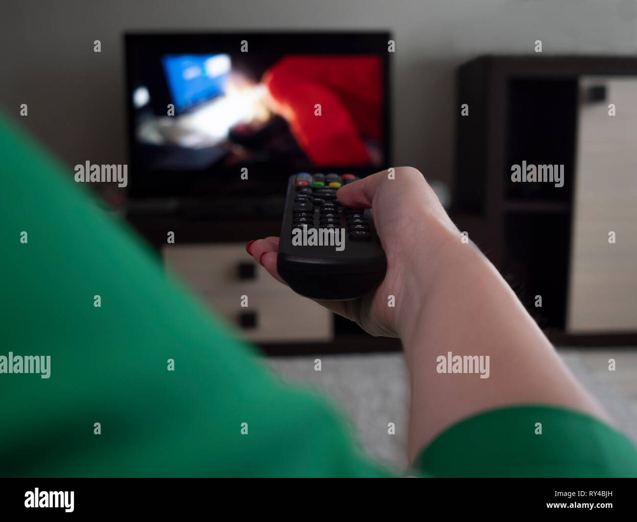 Female hand with tv remote control, rear view Stock Photo