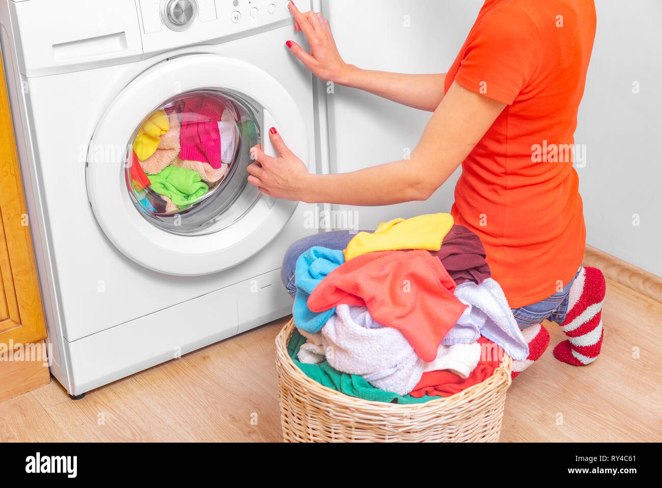 Young woman loads the laundry in the washing machine from the laundry basket before washing
