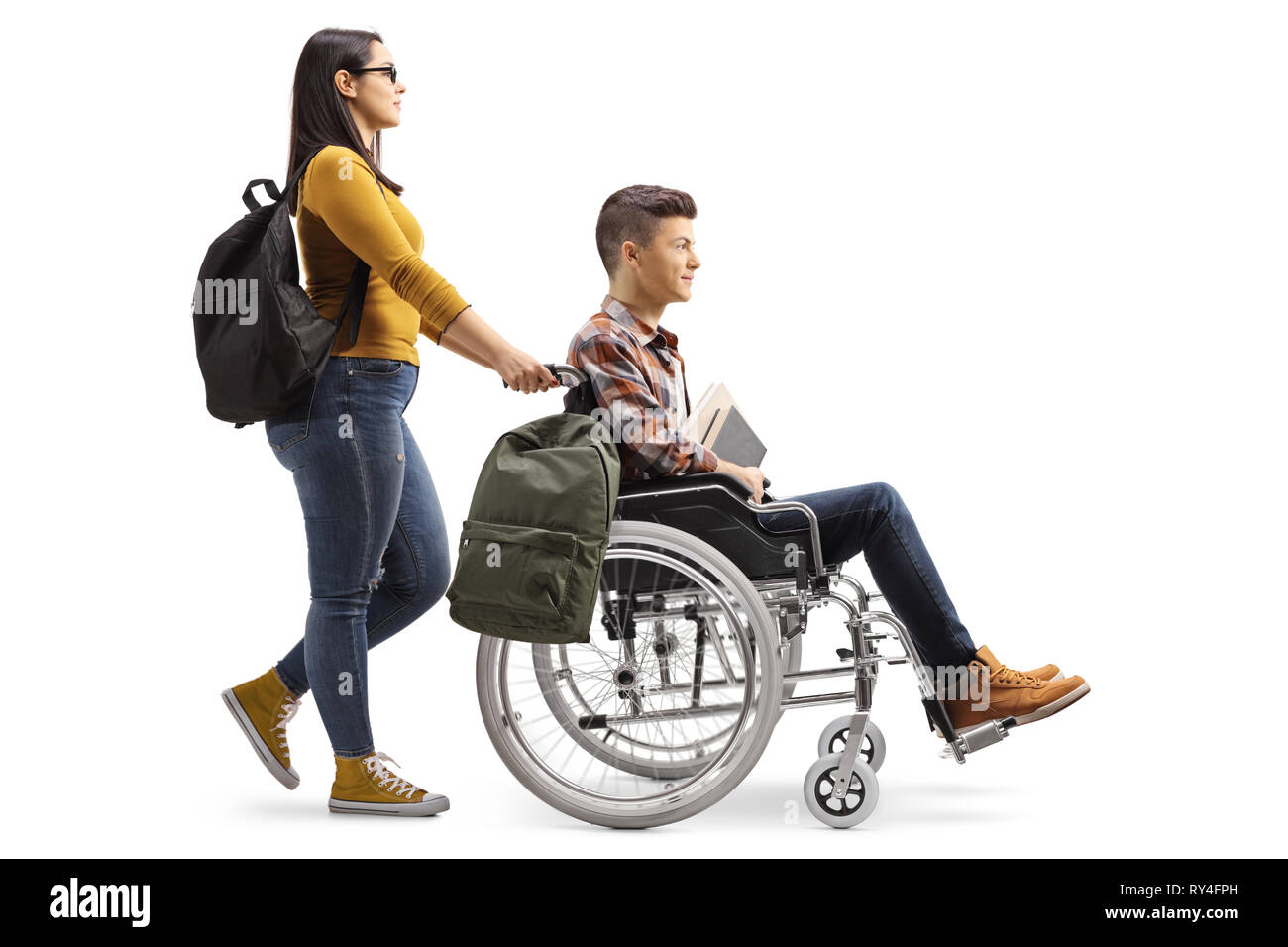 Full length profile shot of a female student pushing a male student in a wheelchair isolated on white background Stock Photo