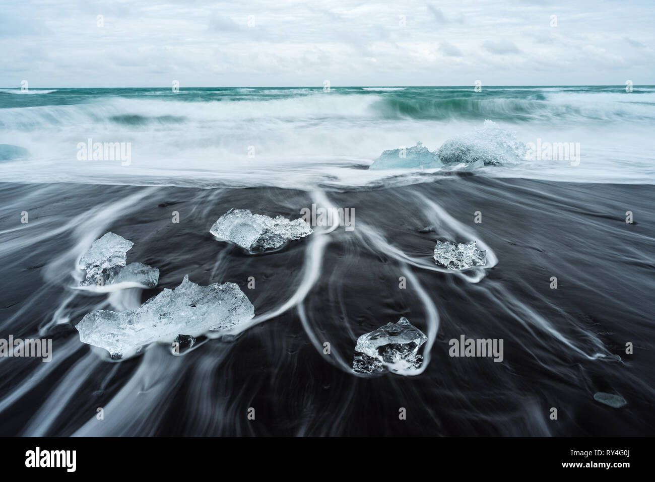 Icy beach in Iceland, Europe. Iceberg on the black volcanic sand on the Atlantic Ocean. Tourist attraction. Amazing landscape, cloudy day Stock Photo