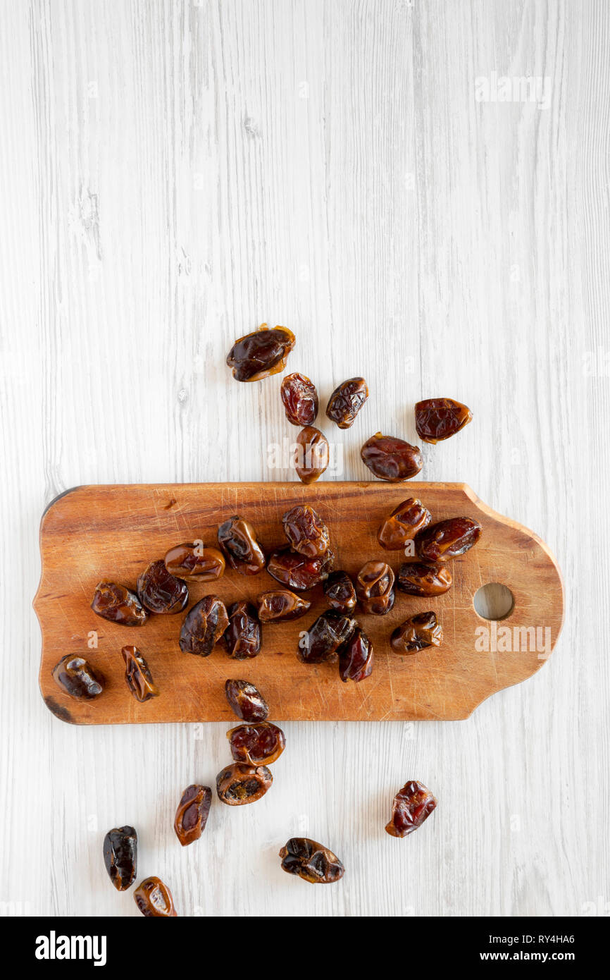 Dried dates on rustic wooden board on a white wooden table, top view ...
