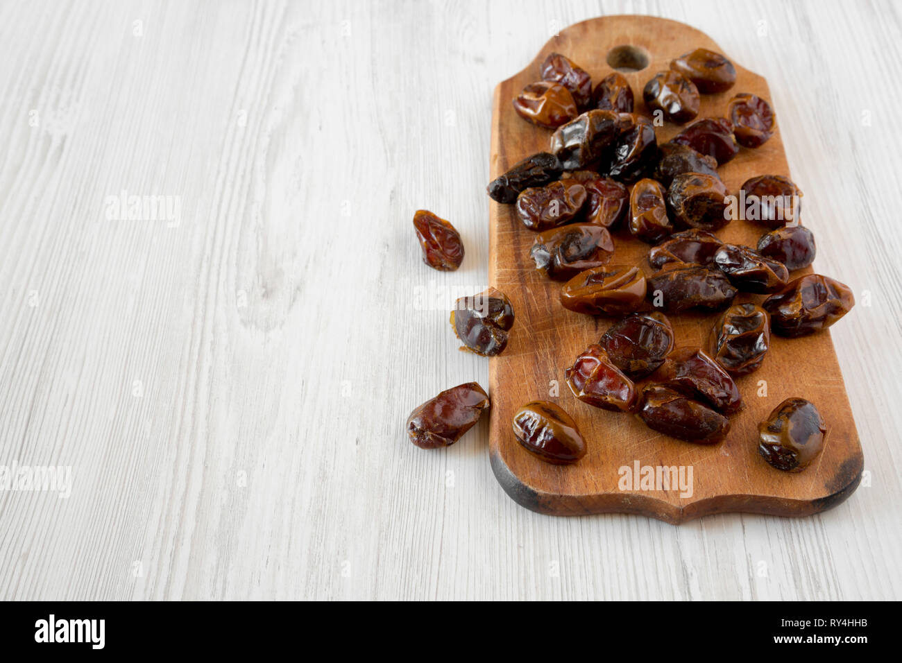 Dried dates on rustic wooden board over white wooden background, side ...