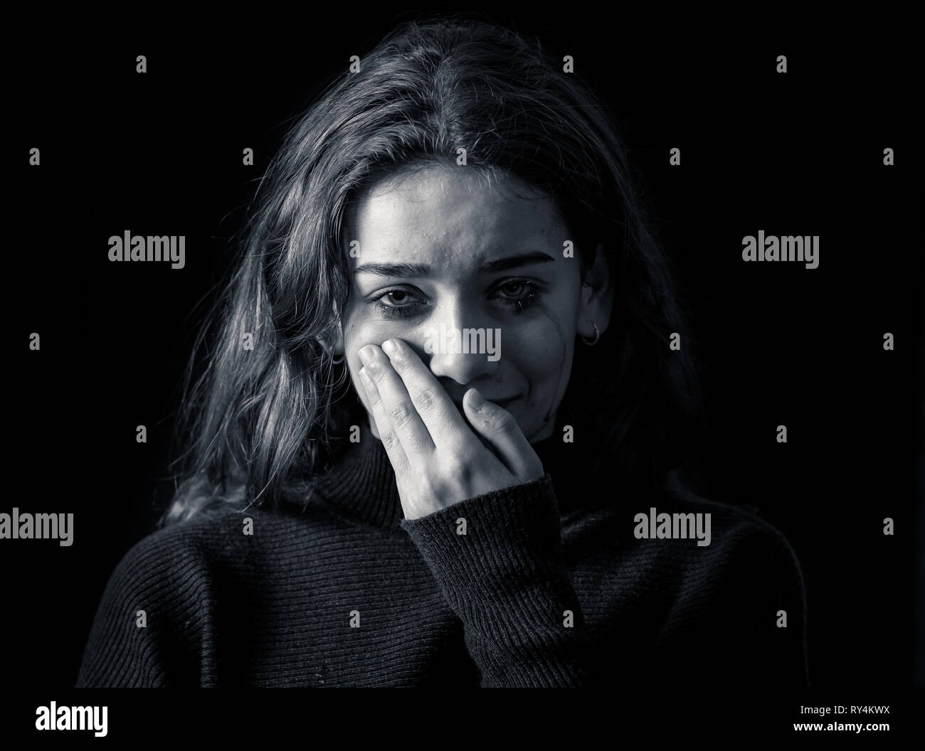 Dramatic closeup portrait of young scared, depressed girl crying alone