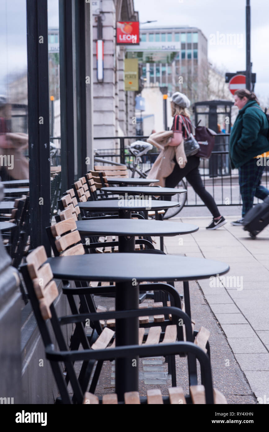 London, UK - March 2019: Empty Chair and tables on pavement outside Starbucks in London Victoria station Stock Photo