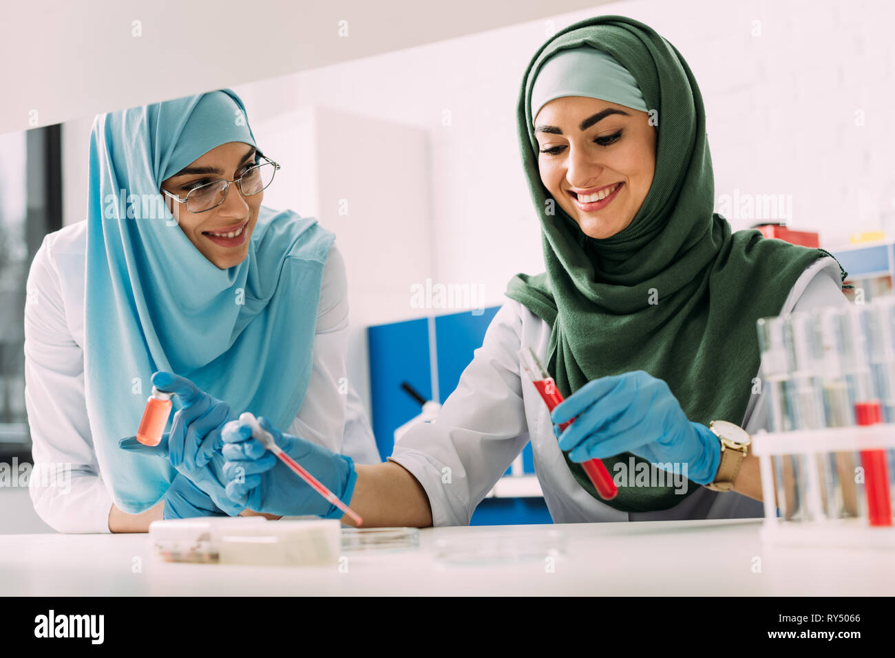 smiling female muslim scientists in hijab with test tube and pipette ...