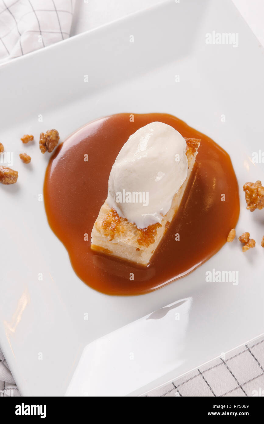 Piece of cheesecake served with ice cream and caramel sauce in white plate Stock Photo