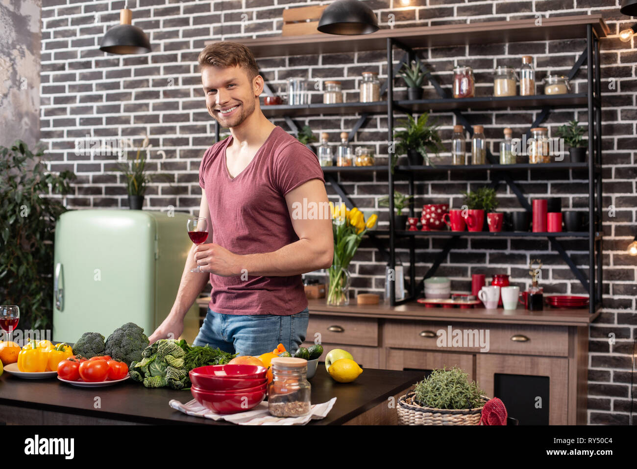 Man with muscles standing in the kitchen and drinking wine Stock Photo ...